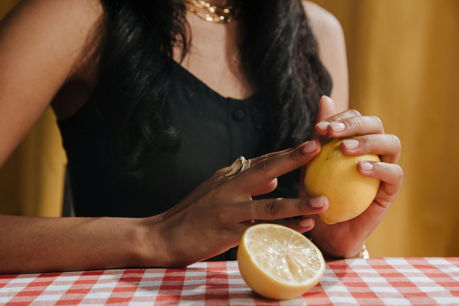 A hand holding a pink vibrator above a decorative glass bowl against a soft background
