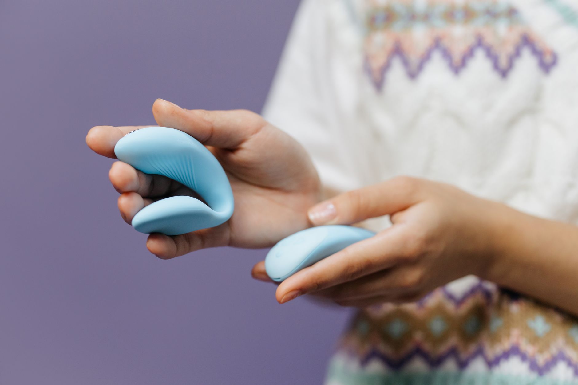 Close-up of hands holding a sleek blue vibrator, symbolizing sensitivity recovery and pleasure restoration